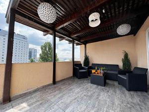 un patio all'ultimo piano con divani e tavoli in un edificio di City View - Luxury Apartment - Sanador Victoriei a Bucarest