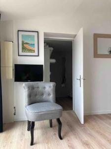 uma sala de estar com uma cadeira e uma televisão em Charmante maison sur l'Ile de Noirmoutier à Barbâtre em Barbâtre