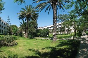 a park with palm trees in front of a building at Labranda Alantur in Alanya