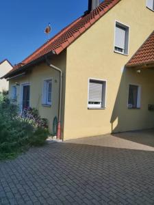 a yellow house with windows and a brick driveway at tAllhouse in Eggolsheim