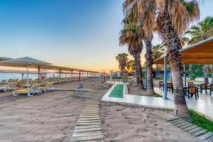 una playa con mesas, sillas y palmeras en Labranda Excelsior Hotel en Side