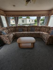 a living room with a large couch and a table at 30 Glenfinart Caravan Park in Dunoon