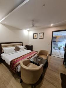 um quarto com uma cama, 2 cadeiras e uma janela em Hotel Central Palace em Dehradun