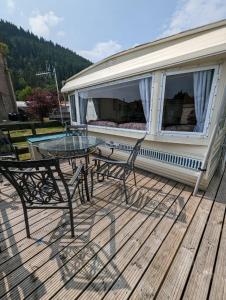 a patio with a table and chairs on a deck at 30 Glenfinart Caravan Park in Dunoon +6 photos