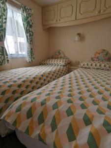 a bedroom with two beds and a window at 30 Glenfinart Caravan Park in Dunoon
