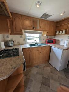 a kitchen with wooden cabinets and a white refrigerator at 30 Glenfinart Caravan Park in Dunoon