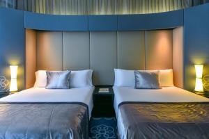 2 Betten nebeneinander in einem Zimmer in der Unterkunft W Doha in Doha