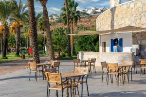 an outdoor patio with tables and chairs and palm trees at Selectum Collection Bodrum in Akyarlar +37 photos