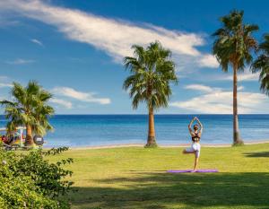 a woman doing yoga on the beach with palm trees at Selectum Collection Bodrum in Akyarlar