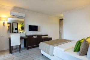 una camera d'albergo con letto, scrivania e TV di Marmaris Bay Resort - Adults Only a Marmaris