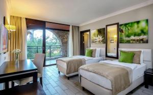 马尔马里斯Marmaris Bay Resort - Adults Only的一间有两张床、一张书桌和一张桌子的酒店房间