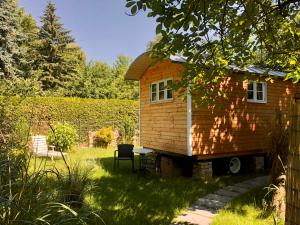 una casetta in un giardino con tavolo e sedia di Zirkuswagen mit Outdoor Whirlpool und Garten a Petershagen