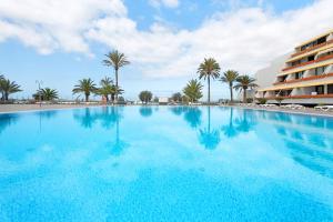 una gran piscina con palmeras y un edificio en Maravilla Over the Ocean, en Costa del Silencio