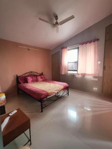 a bedroom with a bed with pink sheets and a window at Ladakh House- 3 BHK Ladakh themed Villa near Matheran in Neral