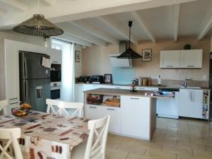 a kitchen with white cabinets and a table and a table and chairs at Le Clos Beldane in Le Tâtre