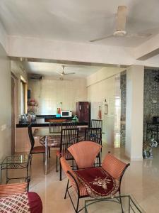 a living room with chairs and a table and a kitchen at Ladakh House- 3 BHK Ladakh themed Villa near Matheran in Neral