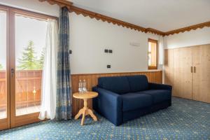 a living room with a blue couch and a table at Hotel Stalon Alpine Chic in San Martino di Castrozza