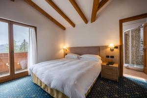 een slaapkamer met een groot bed en een raam bij Hotel Stalon Alpine Chic in San Martino di Castrozza