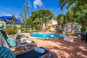una piscina con sillas y sombrilla en Ideal Property Mallorca - Sol de Mallorca 1, en Cala Mesquida