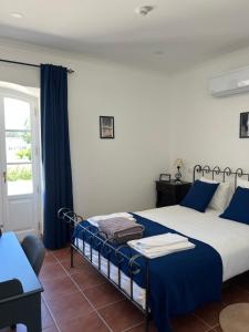 a bedroom with a bed with blue sheets and a window at Quinta da Varzea in Raposa