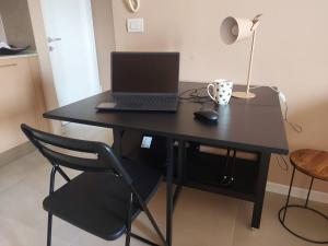 a laptop computer sitting on a black desk with a chair at A spasso in Ventimiglia