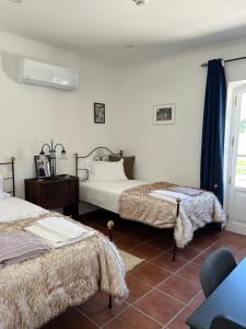 a bedroom with two beds and a table and a window at Quinta da Varzea in Raposa +52 photos