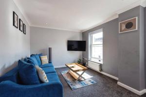 ein Wohnzimmer mit einem blauen Sofa und einem Tisch in der Unterkunft Stunning Refurbished Apartment in Central Cheltenham inc. Parking in Cheltenham