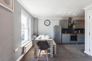 eine Küche mit einem Tisch und einer Uhr an der Wand in der Unterkunft Stunning Refurbished Apartment in Central Cheltenham inc. Parking in Cheltenham