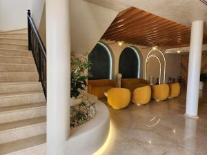 un hall avec des chaises jaunes et un escalier dans l'établissement Hotel Gold, à Vlorë