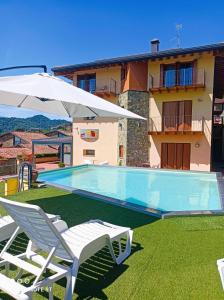 a swimming pool with two lawn chairs and an umbrella at La Marina Resort in Pontida