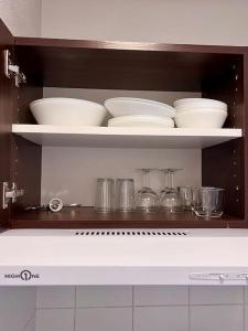 a kitchen shelf with bowls and dishes on it at Appartement proche Disney Paris in Montévrain