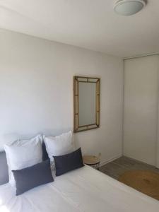 a white bed with blue pillows and a mirror at Appartement proche Disney Paris in Montévrain