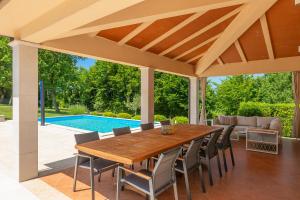 patio con mesa de madera, sillas y piscina en Villa Nona Nina en Poreč