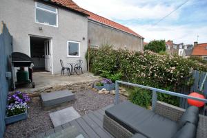 a patio with chairs and flowers and a house at Net Loft- homely accomodation in East Neuk in Anstruther