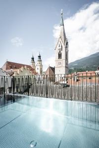 a church with a clock tower and a swimming pool at ADLER Historic Guesthouse in Bressanone