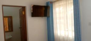 a bathroom with a window with a curtain and a mirror at Aster Suites Kisumu in Awasi
