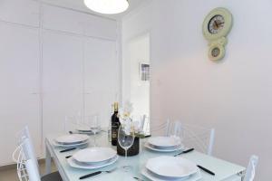 uma sala de jantar branca com uma mesa com pratos e copos em Casa aconchegante com 4 quartos na Vila Madalena em São Paulo