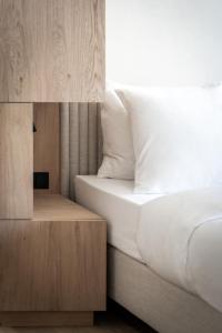 um quarto com uma cama com lençóis brancos e uma mesa de cabeceira em ADLER Historic Guesthouse em Bressanone