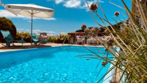 una piscina azul con sombrilla, mesa y sillas en Hotel Rústico Finisterrae en Fisterra
