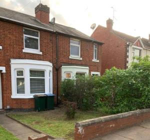a brick house with a green trash can in front of it at Coventry Stays - Terraced House in Wyken