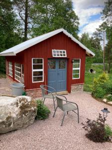 a red shed with a blue door and a chair at Dala Cottage in Ulriksberg