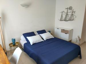 - une chambre avec un lit doté de draps bleus et d'oreillers blancs dans l'établissement Grand F2 Bastia, Port de Toga, Terrasse Vue Mer, à Bastia