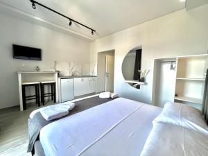 a bedroom with a large white bed and a kitchen at Apartments Klajdi in Sarandë