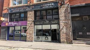 una tienda frente a un edificio de ladrillo con ventanas en Cocoon @ International Inn + Apartments, en Liverpool