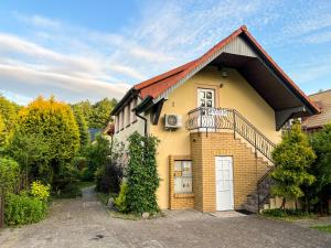 a yellow house with a white door and a balcony at Apartamenty Zacisze 1 in Poddąbie