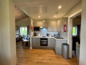 a kitchen with white appliances and a living room at Breckland Lodge 3 with Hot Tub in Belladrum