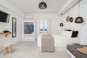 a white bedroom with a bed and a tv at Celestial Seaview Apartments-Portara in Naxos Chora