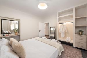 a white bedroom with a large bed and a mirror at My Pixida Apartments in Rhodes Town
