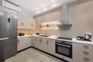 a kitchen with white cabinets and a stainless steel refrigerator at My Pixida Apartments in Rhodes Town +41 photos