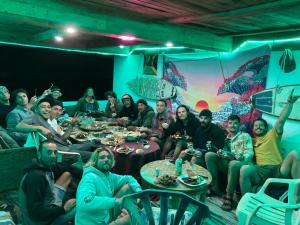 un groupe de personnes assises à des tables dans une pièce dans l'établissement EL Faro Surfstay, à Tamri